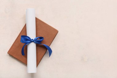 Mavi kurdeleli diploma ve beyaz arka plan kitabı