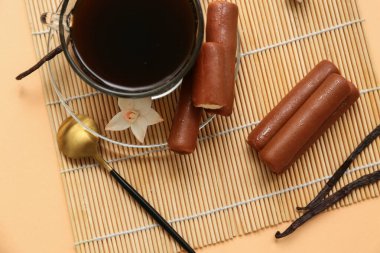 Vanilya aromalı lezzetli çikolatalı kremalı atıştırmalıklar ve bej arka planda bir fincan kahve.