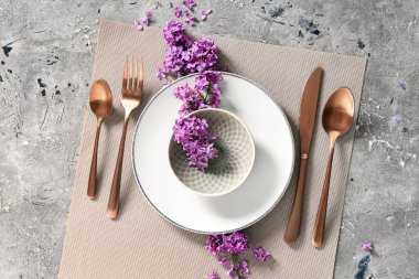 Gri grunge arka planında leylak çiçekleri olan güzel bir masa.