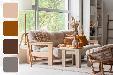 Interior of light living room with autumn decor, sofa and wooden table. Different color patterns