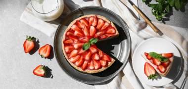 Gri arka planda naneli çilekli turta ve bir sürahi taze süt.