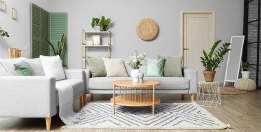 Gri kanepeleri, kahve masasında vazosu ve çiçekleri olan modern oturma odasının içinde.