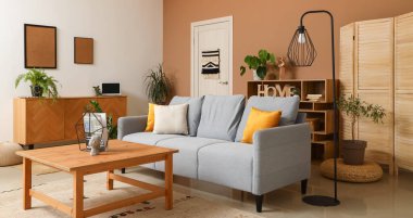 Modern oturma odasının içinde gri kanepe, standart lamba ve ahşap sehpa var.