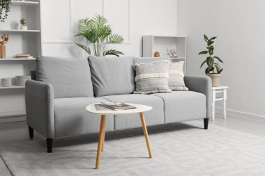 Kanepe, masa ve raf üniteleriyle aydınlık oturma odasının içinde.