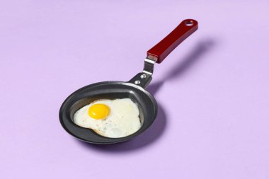 Leylak arkaplanda kalp şeklinde kızarmış yumurta ile kızartma tavası.