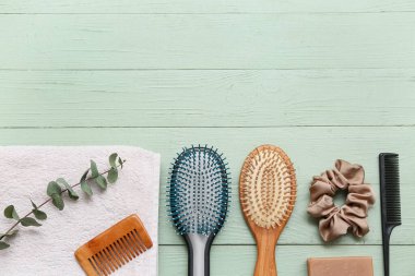 Towel with hair brushes, combs and silk scrunchy on green wooden background