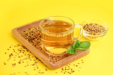 Sarı zemin üzerinde bir bardak lezzetli karabuğday çayı ve nane şekeri.