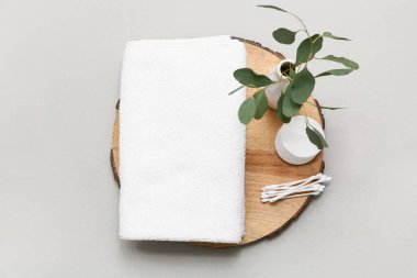 Temiz yumuşak havluyla kompozisyon, ahşap tepsi, gri arka planda pamuk pedler ve tomurcuklar