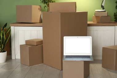 Yeşil duvarın yanındaki kutuları taşıyan boş bir dizüstü bilgisayar.