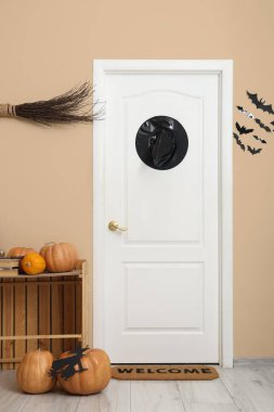 Interior of hallway decorated for Halloween with door, witch hat and pumpkins