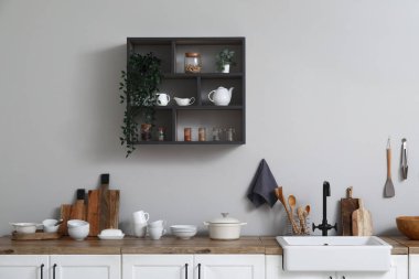 Interior of light kitchen with sink, dishes and shelf
