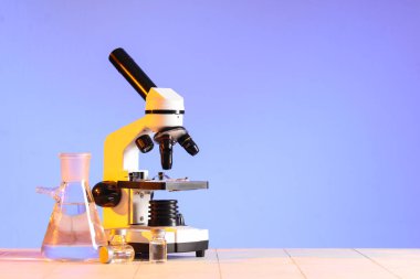 Laboratuvar matarası ve beyaz fayansların üzerindeki ampullerle modern mikroskop.