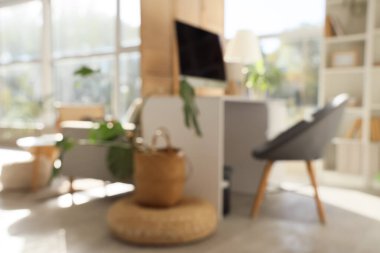 Blurred view of office with workplace, folding screen and plants