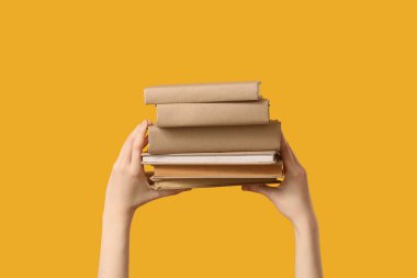 Sarı arka planda kitapları tutan eller