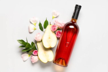 Gül çiçekli bir şişe şarap, armut yarımları ve beyaz arka planda yapraklar