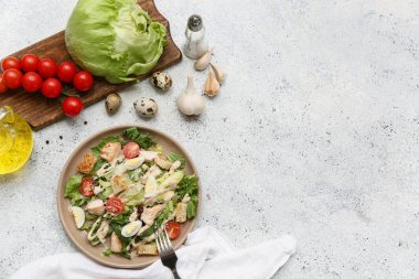 Lezzetli tavuklu Sezar salatası ve beyaz arka planda malzemeler.