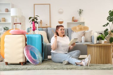 Young woman making list of things for trip at home
