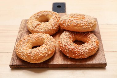 Tahta arka planda susam tohumlu lezzetli simit tahtası, yakın plan.