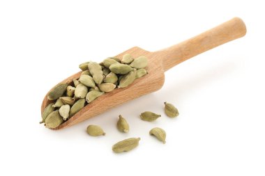 Beyaz arka planda kakule baharatlı ahşap kepçe.