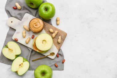 Cutting board with fresh apple sandwich with sweet peanut butter on white background