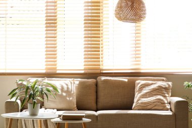 Rahat kahverengi kanepe ve oturma odasının penceresinin yanındaki masalar.