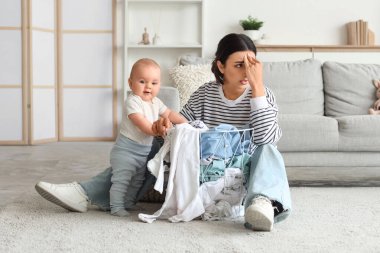 Genç anne doğum sonrası depresyondan muzdarip. Kirli çamaşırları ve bebeği evde.