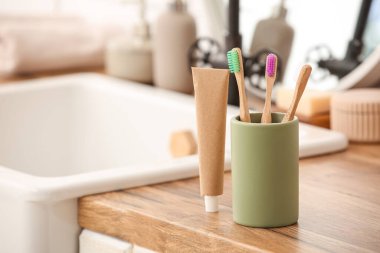 Banyoda lavabonun yanında bambu diş fırçası ve macun tüpü olan tutucu.
