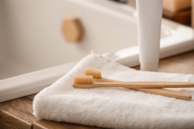 Havlulu bambu diş fırçaları ve banyoda lavabonun yanında bir tüp macun.