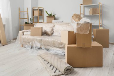 Sofa with film and boxes in living room on moving day