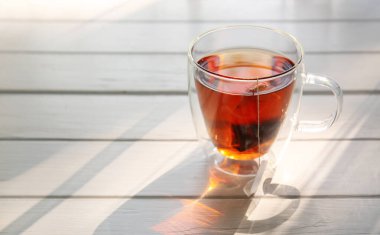 Beyaz ahşap masada bir bardak siyah çay.