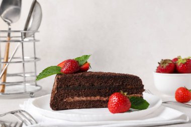 Beyaz arka planda çilek ve nane yapraklı bir tabak çikolatalı kek.