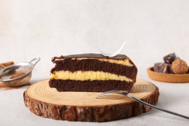 Tahta tahta tahta üzerinde bir parça çikolatalı pasta ve beyaz arka planda şekerler.