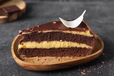 Koyu arkaplanda bir parça çikolatalı pasta olan ahşap tabak, yakın plan.