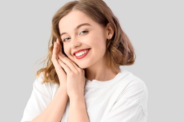 Smiling young woman with bob hairstyle on grey background
