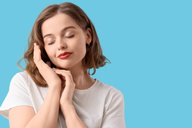 Mavi arka planda kısa saç stili olan güzel bir genç kadın.