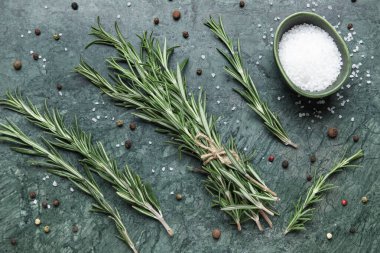 Biber taneli taze biberiye dalı ve yeşil arka planda bir kase tuz.