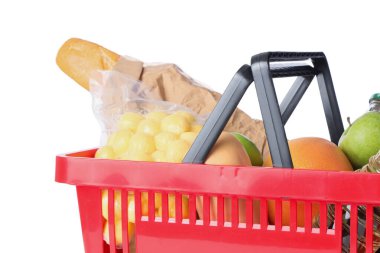 Beyaz zemin üzerinde farklı taze ürünler bulunan kırmızı alışveriş sepeti, yakın plan