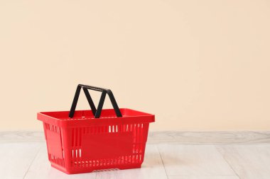 Bej duvarın yanında kırmızı alışveriş sepeti