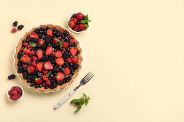 Farklı taze böğürtlenli tatlı tart ve sarı arkaplanda nane.