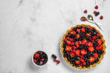 Beyaz arka planda farklı taze böğürtlenli tatlı tart.