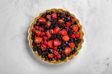 Beyaz arka planda farklı taze böğürtlenli tatlı tart.