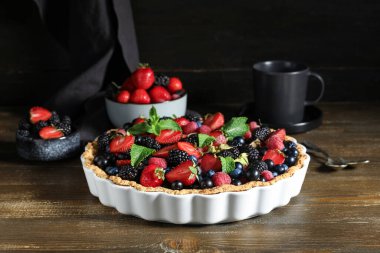 Farklı taze böğürtlenli tatlı tart ve ahşap masada nane.