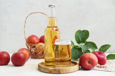 Beyaz arka planda meyveli bardak ve bir şişe taze elma şarabı.