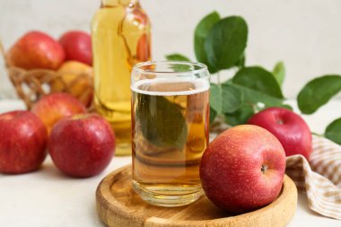 Beyaz arka planda meyveli bardak ve bir şişe taze elma şarabı.