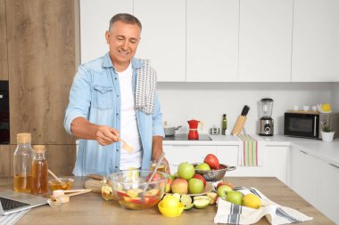 Şekerli olgun bir adam mutfakta elma suyu yapıyor.