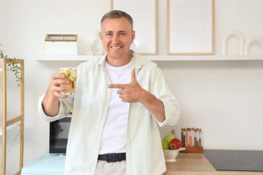 Mature man pointing at apple cider in kitchen
