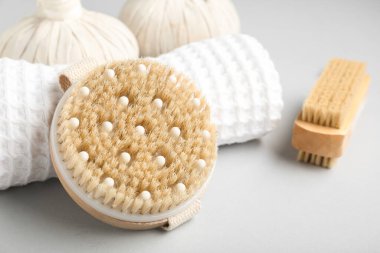 Gri arka planda vücut masajı fırçaları ve bitki torbaları, yakın plan.