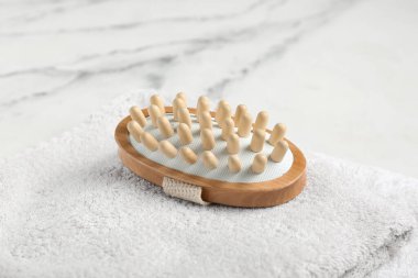 Beyaz arka planda vücut masajı fırçası ve havlu, yakın plan.