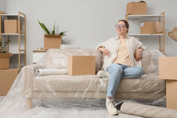 Odadaki koltukta oturan taşınma kutusuyla genç bir kadın.