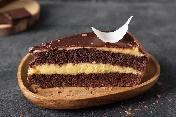Koyu arkaplanda bir parça çikolatalı pasta olan ahşap tabak, yakın plan.